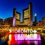 Dazzling Toronto skyline with iconic sign and fountain at dusk.