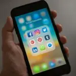 A smartphone displaying various social media icons held in a hand, showcasing modern communication apps.